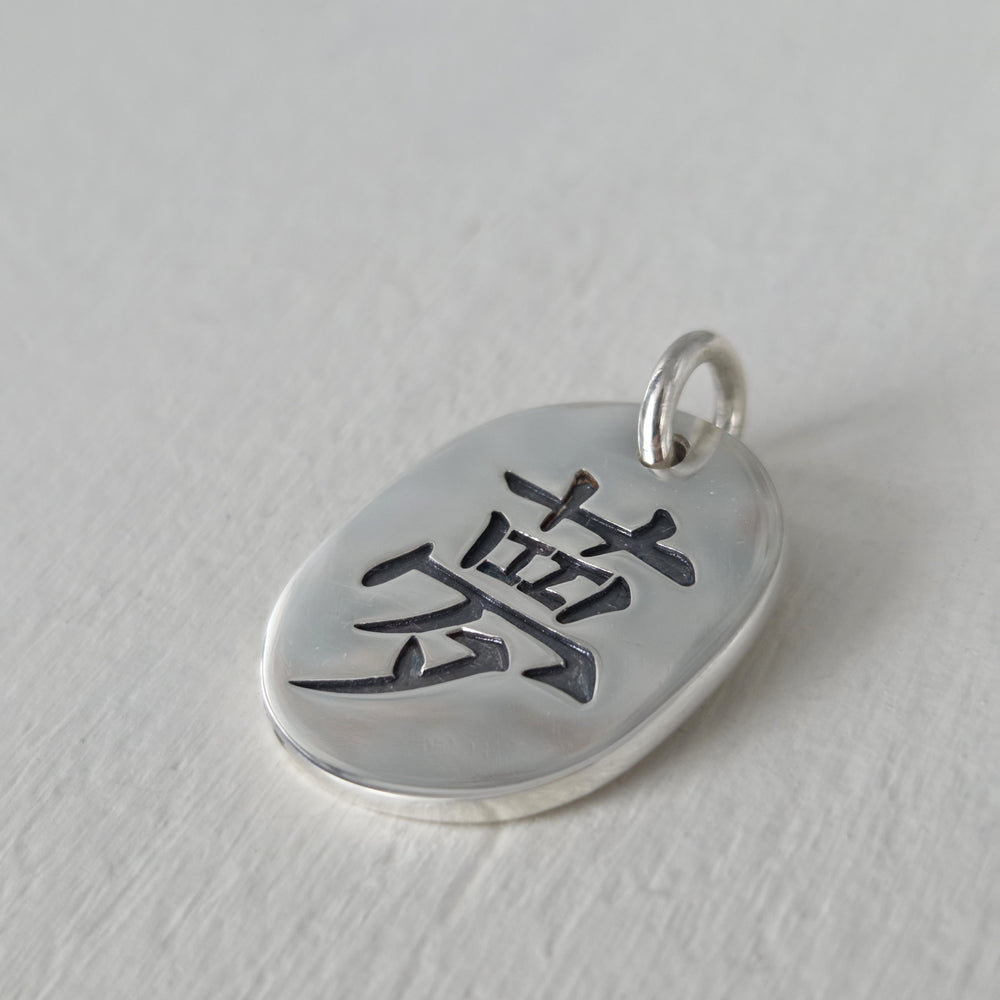 Medallón artesanal de plata 950 con kanji del amor y acabado envejecido