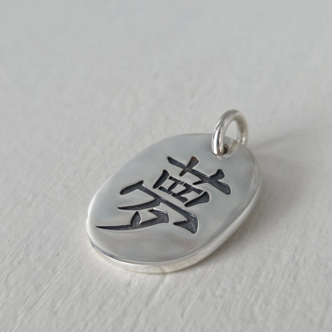 Medallón artesanal de plata 950 con kanji del amor y acabado envejecido