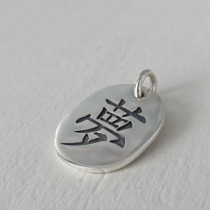 Medallón artesanal de plata 950 con kanji del amor y acabado envejecido