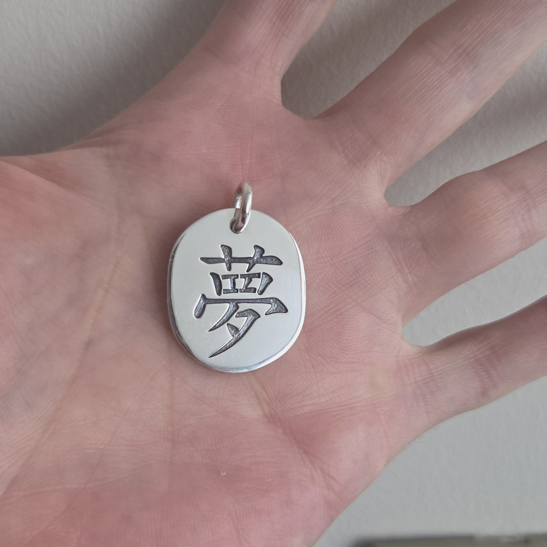 Detalle del grabado del símbolo japonés del amor en colgante de plata