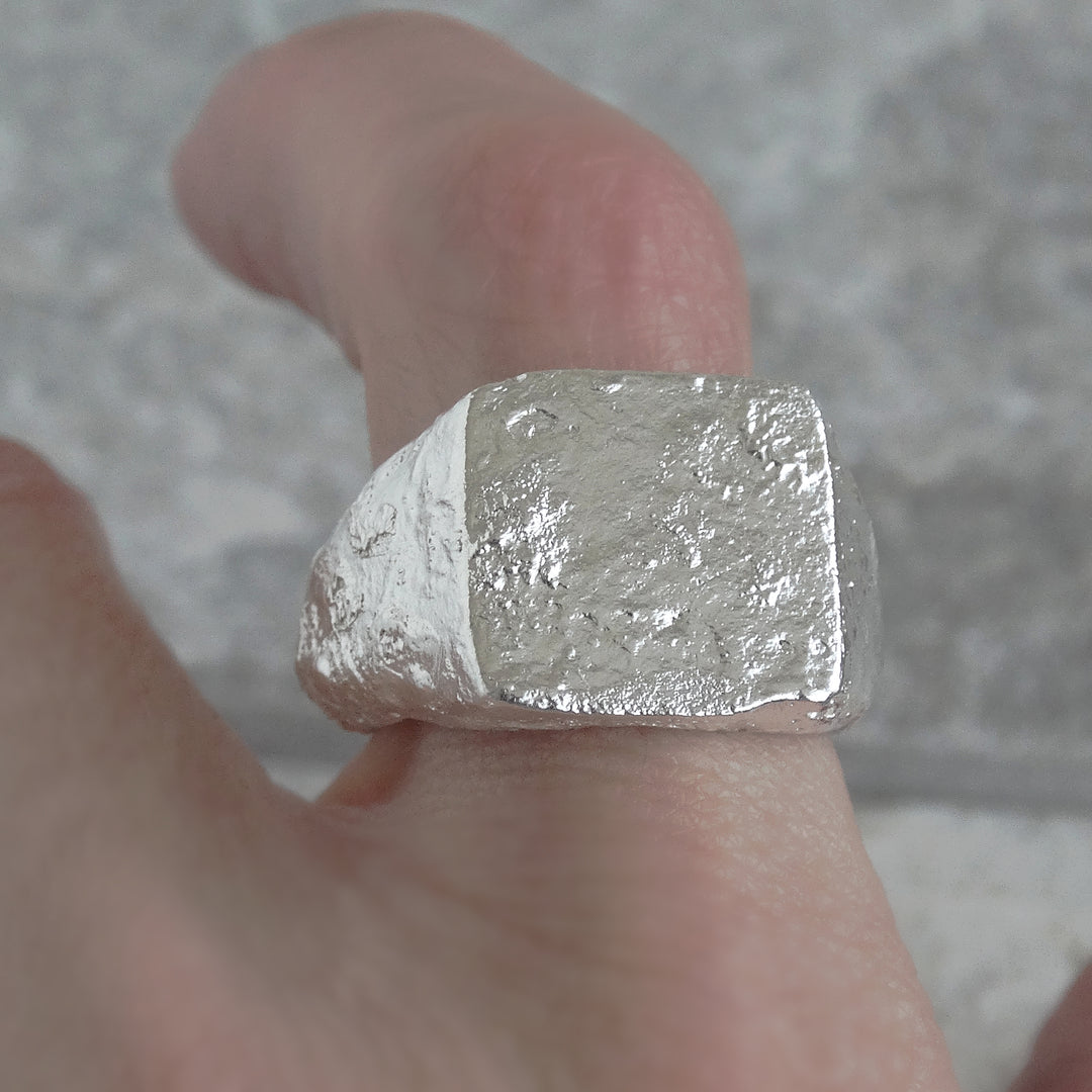 Detalle frontal de anillo de sello con acabado reticulado hecho a mano