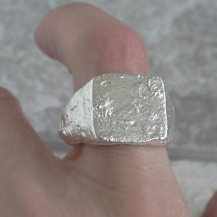 Detalle frontal de anillo de sello con acabado reticulado hecho a mano